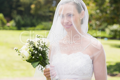 Bride looking away through veil in garden