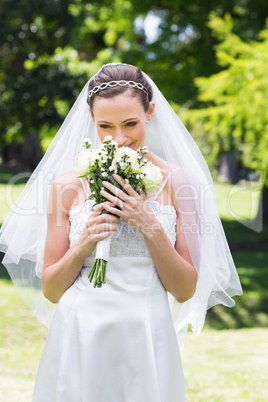 Bride smelling fresh flowers in garden