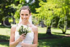 Attractive bride holding flower bouquet in garden