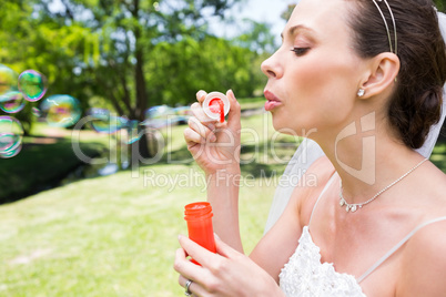 Bride blowing bubbles in garden