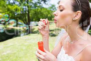 Bride blowing bubbles in garden