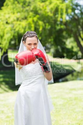 Bride with boxing gloves punching in park