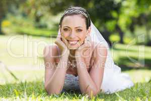 Bride in wedding gown lying on grass