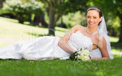 Beautiful bride lying on grass in park