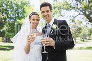 Newlywed couple toasting champagne in park