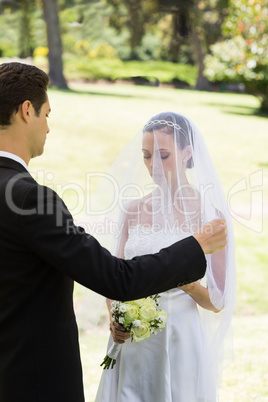 Groom about to lift veil of bride