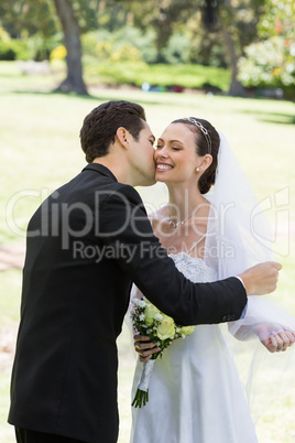 Groom kissing bride in garden