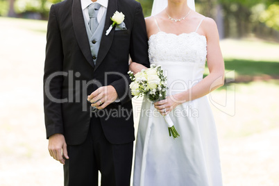 Newlywed couple holding hands in park