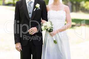 Newlywed couple holding hands in park