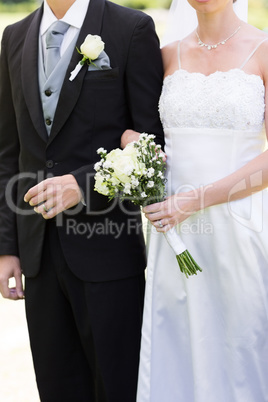 Bride and groom holding hands in park