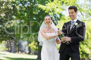 Newlywed couple popping cork of champagne