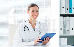 Happy female doctor holding digital tablet