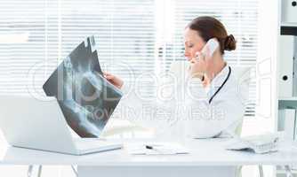 Doctor using telephone while studying Xray