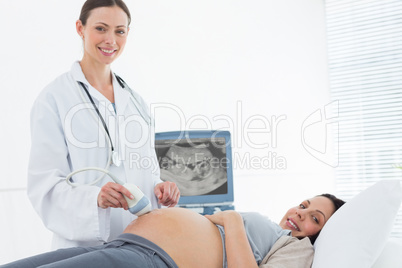 Smiling doctor performing ultrasound on pregnant woman Smiling doctor performing ultrasound on pregnant woman