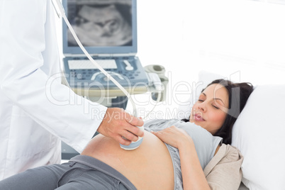 Male doctor performing ultrasound on pregnant woman