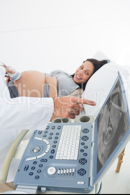 Doctor showing ultrasound monitor to pregnant woman