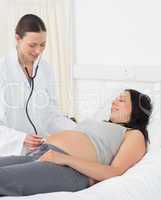 Doctor examining stomach of pregnant woman