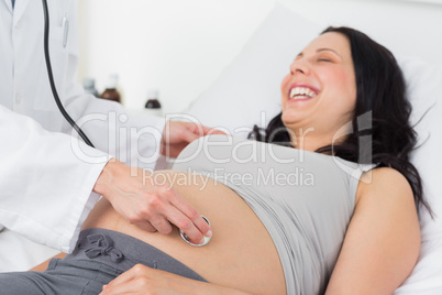 Happy pregnant woman being checked by doctor