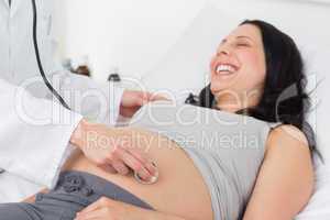 Happy pregnant woman being checked by doctor