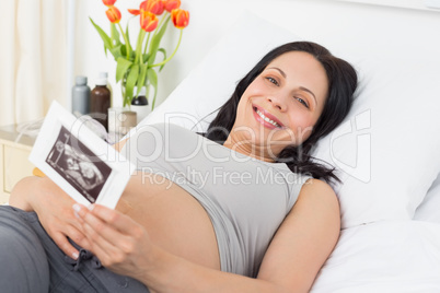Smiling pregnant woman holding sonography report