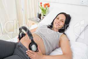 Happy pregnant woman with headphones on her belly