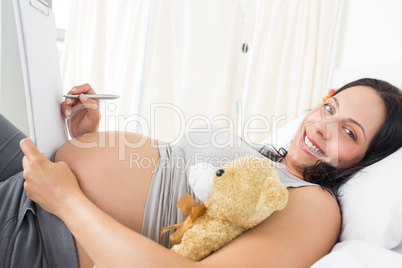 Portrait of pregnant woman writing on clipboard