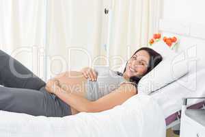 Smiling pregnant woman lying in hospital