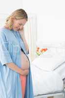 Smiling pregnant woman looking at belly
