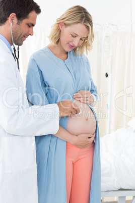 Male doctor checking belly of pregnant woman