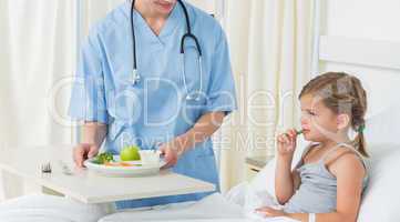 Doctor feeding breakfast to sick girl