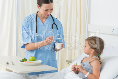 Doctor feeding meal to sick girl