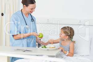 Smiling doctor giving apple to sick girl