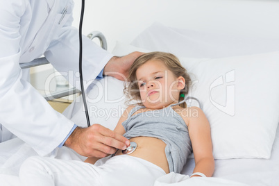 Doctor checking stomach of sick girl