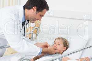 Smiling doctor checking thyroid glands of ill girl