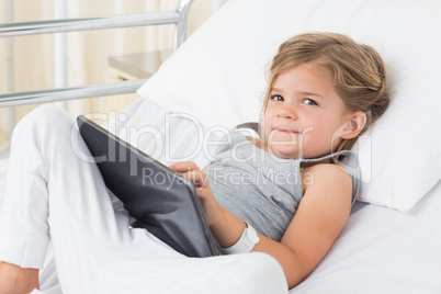 Sick girl with digital tablet in hospital bed