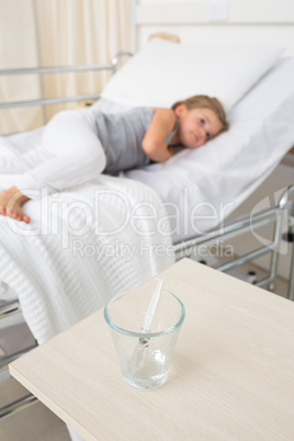 Syringe in glass with girl resting in hospital