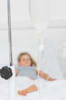 IV drip with ill girl in hospital bed
