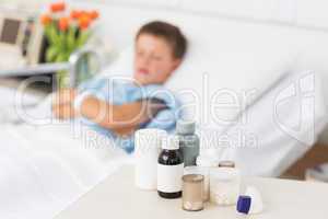 Medicines on table with boy in bed