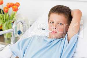 Boy in hospital bed with thermometer