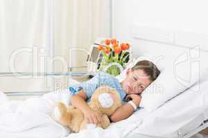 Boy sleeping with teddy bear in hospital