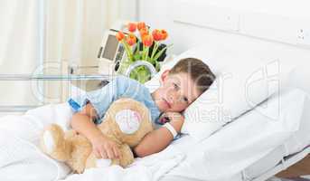 Boy lying with teddy bear in hospital