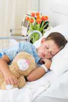 Boy with teddy bear sleeping in hospital