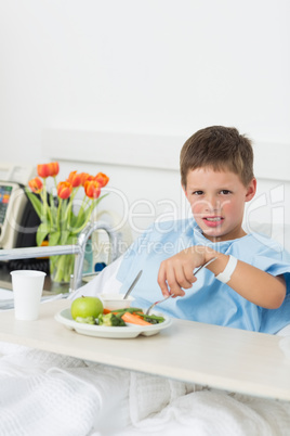 Sick boy having food in hospital bed