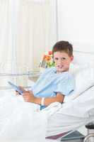 Sick boy holding digital tablet in hospital