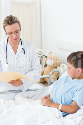 Doctor reading report of sick boy