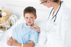 Doctor comforting sick boy in ward