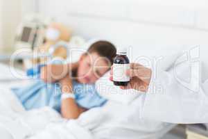 Doctor holding cough syrup with boy in hospital