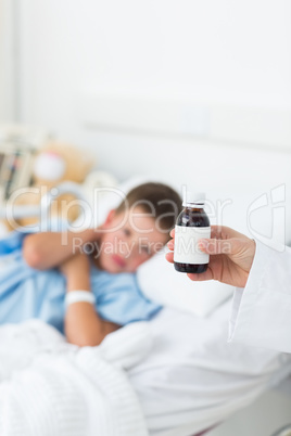 Doctor holding cough syrup with boy in hospital