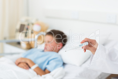 Doctor holding thermometer with boy in hospital