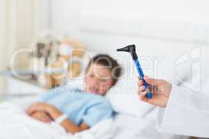 Doctor holding otoscope with boy in hospital
